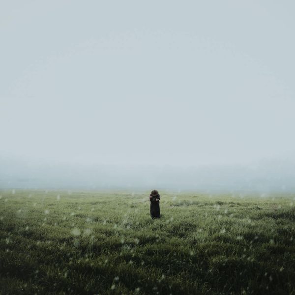 Person meditating in a serene environment with soft green lighting.